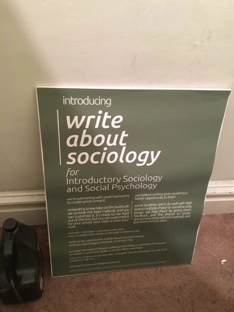 A large green and white poster leaning against a wall that reads "introducing write about sociology for Introductory Sociology and Social Psychology."